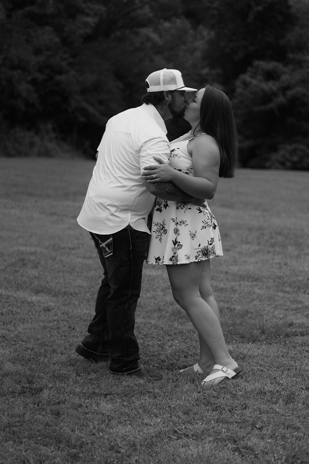 Black and white photo of a couple kissing in an open field