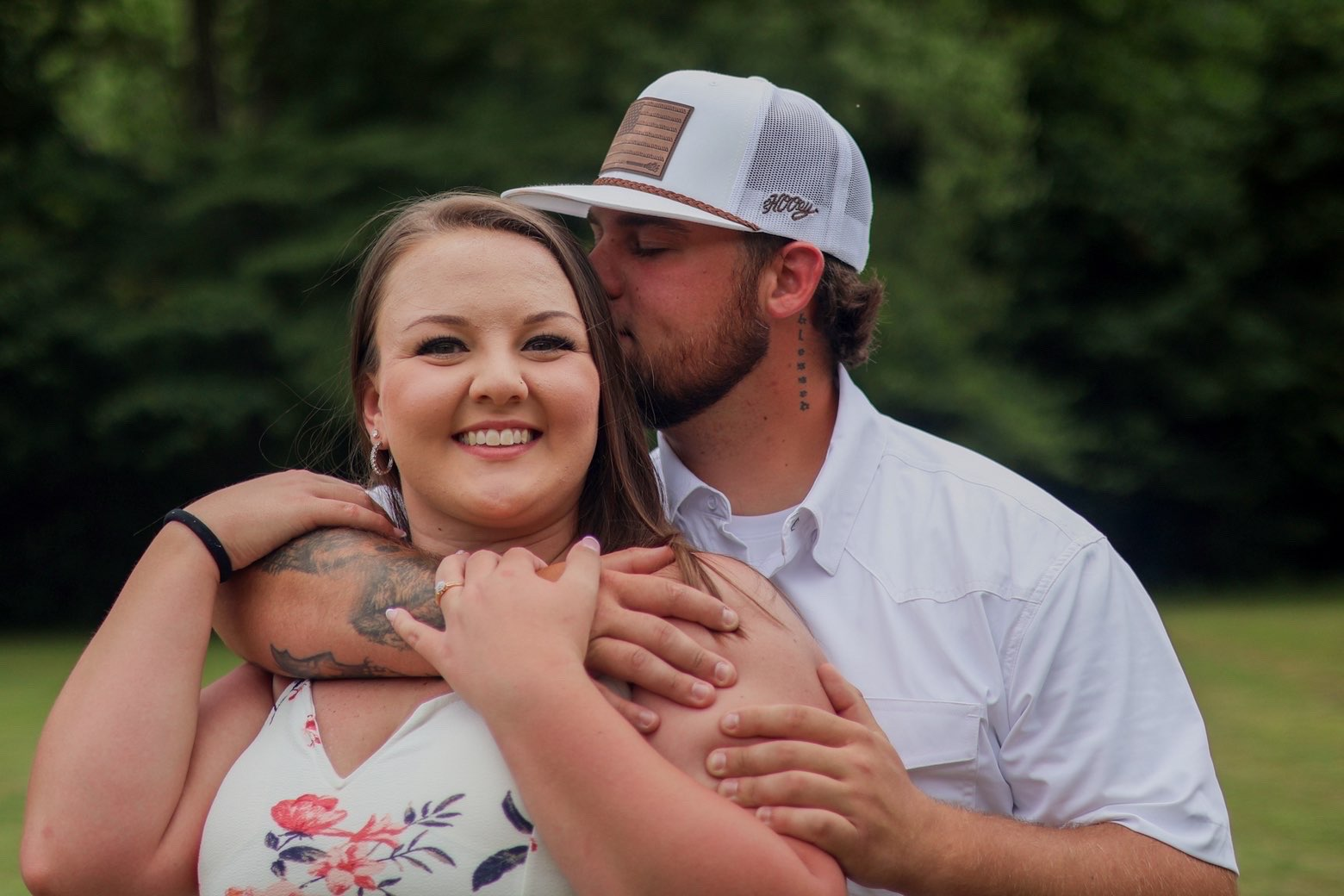 Man embracing his fiancee from behind in a field
