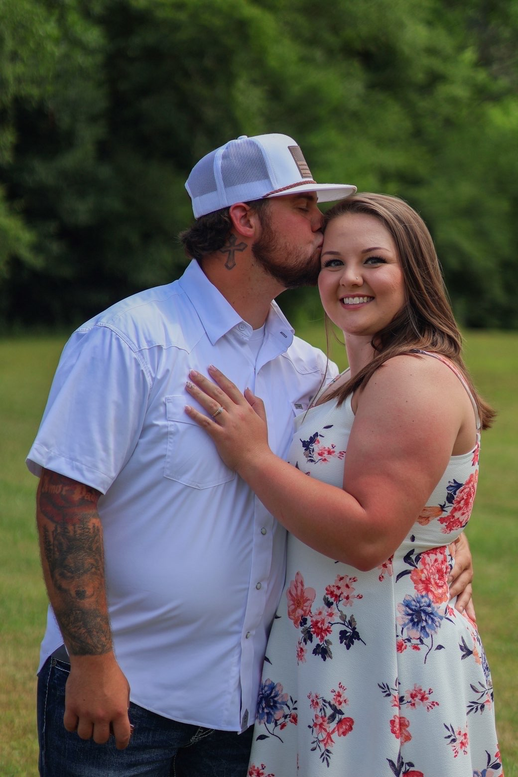 Man kissing his fiancee on the forehead as she smiles