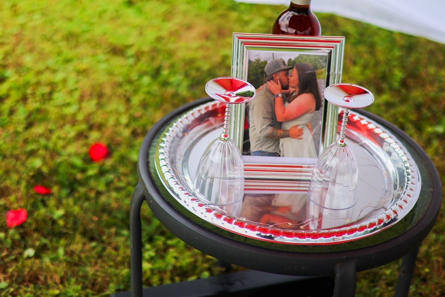 Framed engagement photo styled with glasses and rose petals
