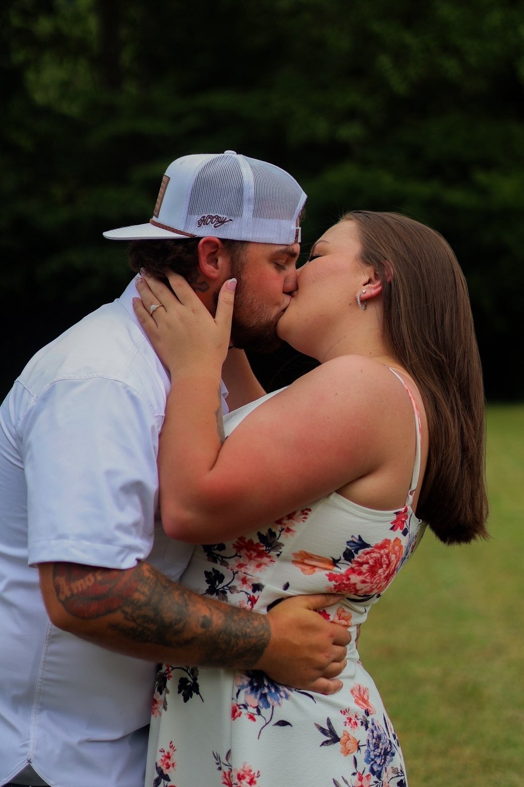 Engaged couple sharing a kiss in a sunlit field
