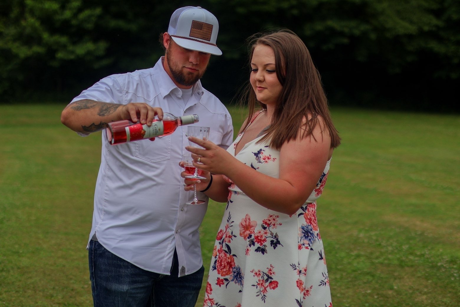 Man pouring rose wine into a glass for his fiancee
