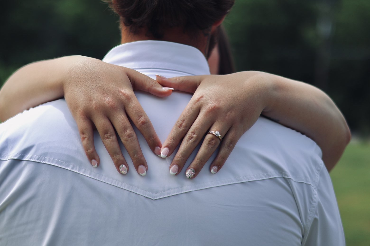 Close up of an engagement ring as the couple embraces